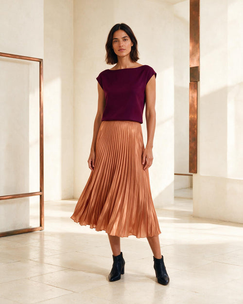 Modelo usando saia midi plissada em tom cobre